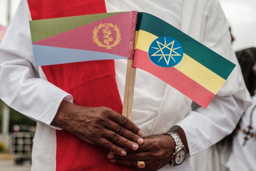 In this file photo taken on November 09, 2018 a man holds National flags of Eritrea (left) and Ethiopia as he waits for the arrival of Eritrea's President at the airport in Gondar, nothern Ethiopia.  (Photo by EDUARDO SOTERAS / AFP)