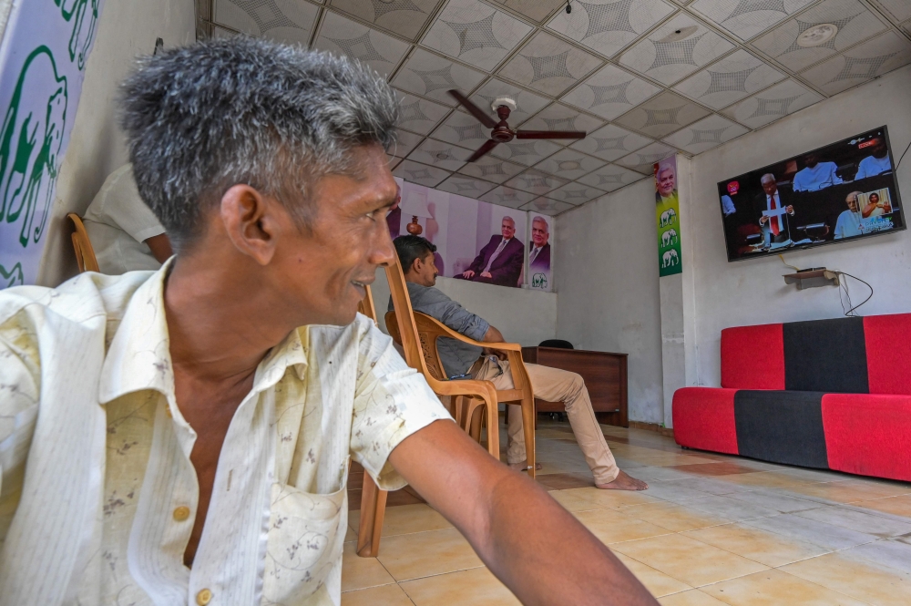 People watch Sri Lanka's President Ranil Wickremesinghe addressing the parliament, on a television in Colombo on March 22, 2023. (Photo by Ishara S. Kodikara / AFP)
