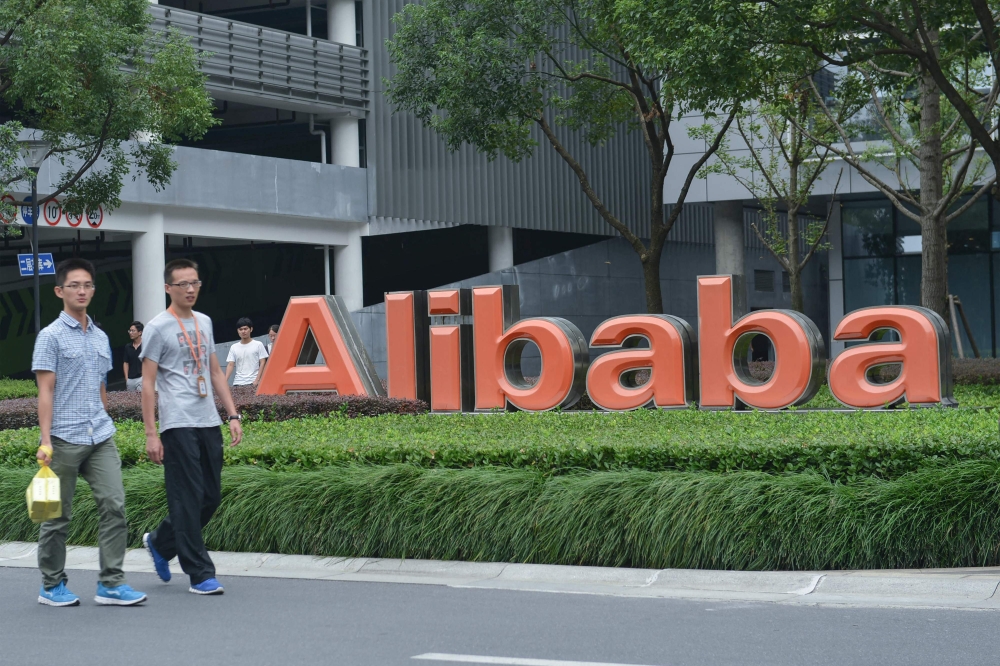 This file photo taken on May 27, 2022 shows staff members walking past the logo of Chinese e-commerce giant Alibaba at its headquarters in Hangzhou, in China's eastern Zhejiang province. Photo by AFP