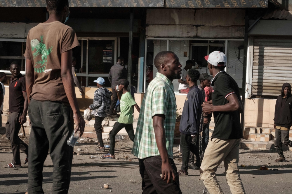 Protesters walk in front of a looted shop in Nairobi, on March 30, 2023 during a protest called by the opposiion coalition 