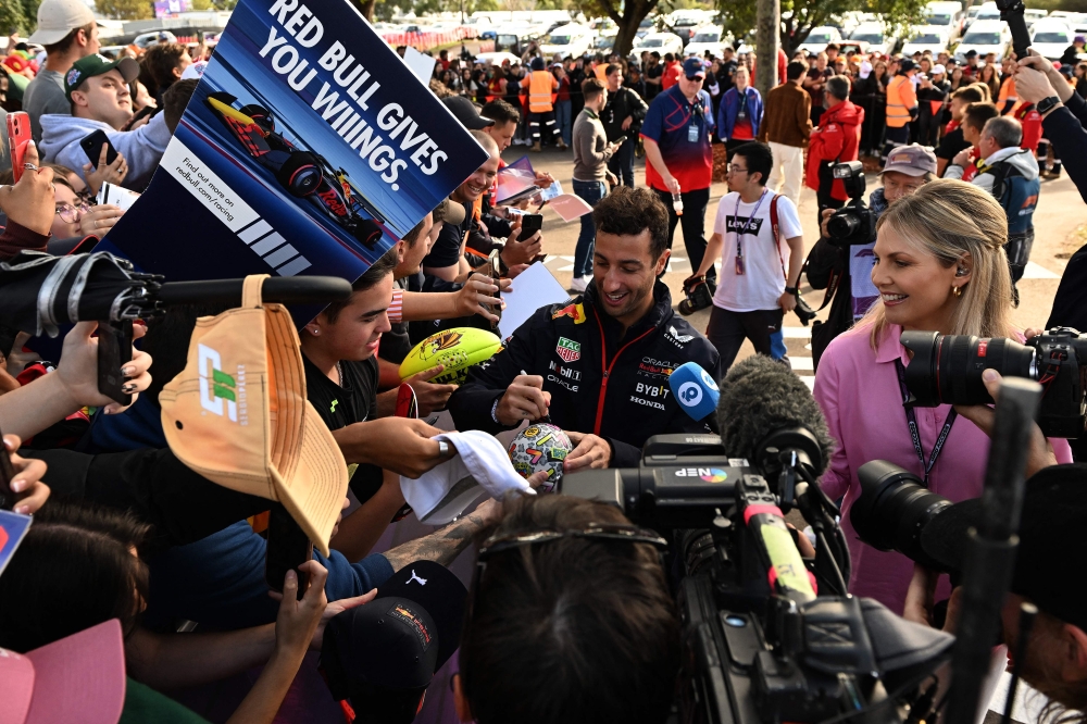 Red Bull Racing's Australian reserve driver Daniel Ricciardo signs autographs to fans ahead of the first practice session of the 2023 Formula One Australian Grand Prix at the Albert Park Circuit in Melbourne on March 31, 2023. Photo by Paul CROCK / AFP