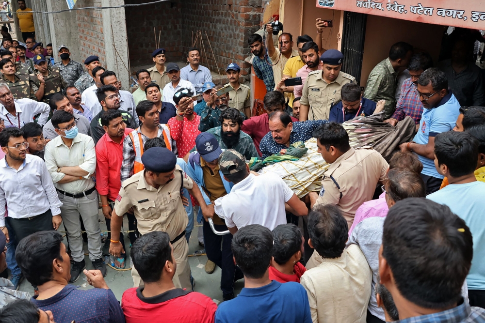 Rescue and security personnel carry a devotee on a stretcher who was injured after the floor covering a stepwell collapsed at a temple in Indore on March 30, 2023. Photo by AFP