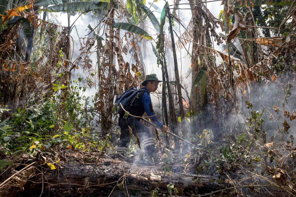 A member of the fire and rescue team attends to a forest fire on a mountain-side in Nakhon Nayok province, northeast of Bangkok on March 31, 2023. Photo by Jack TAYLOR / AFP
