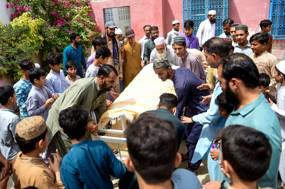 Mourners carry the coffin of a stampede victim for his funeral in Karachi on April 1, 2023. (Photo by Rizwan Tabassum / AFP)