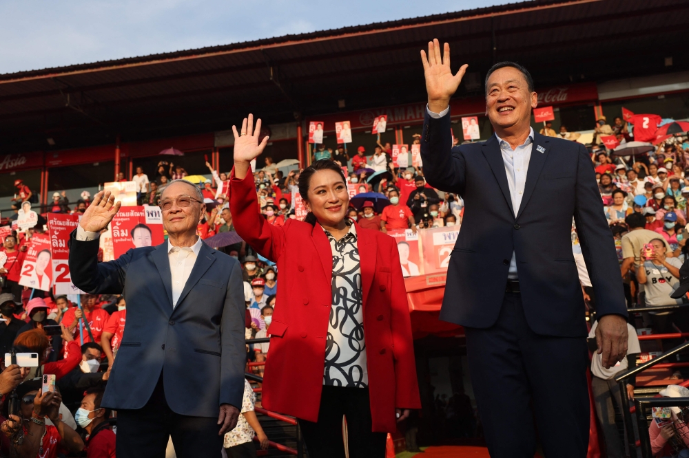 Thai candidates for prime minister Paetongtarn Shinawatra (C), Srettha Thavisin (R) and Chaikasem Nitisiri (L) wave to the crowd during an election rally for Thailand's main opposition Pheu Thai party at the Thunder Dome Stadium in Nonthaburi, north of the capital Bangkok, on April 5, 2023. (Photo by Jack Taylor / AFP)
 