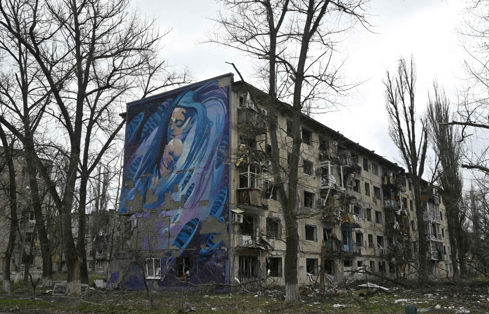A mural depicting a woman with a child is seen on a wall of a heavily damaged residential building in the frontline town of Avdiivka, Donetsk region on April 4, 2023. (Photo by Genya Savilov / AFP)
 