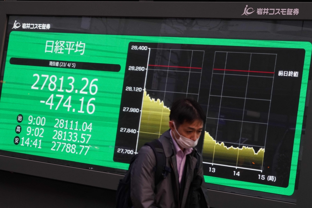 A man walks past an electronic quotation board displaying the closing numbers of share prices of the Tokyo Stock Exchange in Tokyo on April 5, 2023. (Photo by Kazuhiro Nogi / AFP)