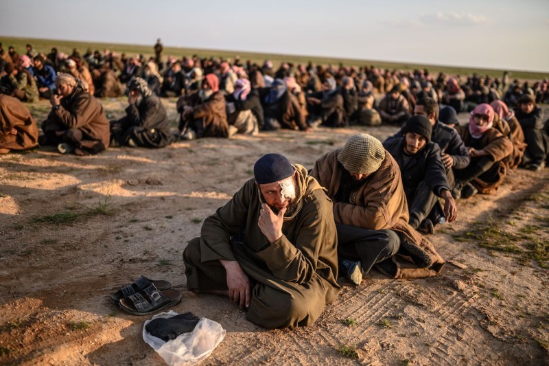 Men suspected of being Islamic State fighters wait to be searched by members of the Kurdish-led Syrian Democratic Forces after leaving the group's last holdout of Baghouz, Syria, on Feb. 22. (Bulent Kilic/AFP/Getty Images)