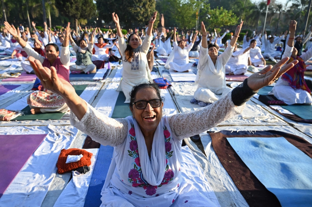 People practice yoga during the morning at a park in Amritsar in the northwestern Indian state of Punjab on April 9, 2023. (Photo by Narinder Nanu / AFP)