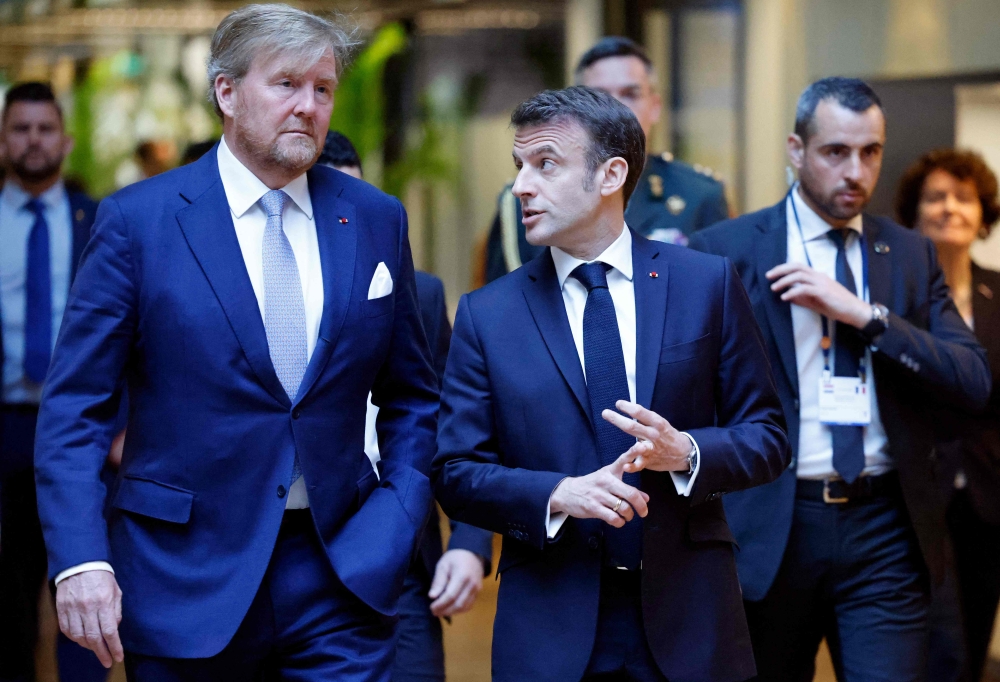 France's President Emmanuel Macron (C) and King Willem-Alexander of the Netherlands (L) walk during a visit of the experimental quantum physics laboratory of the University of Amsterdam before signing a 