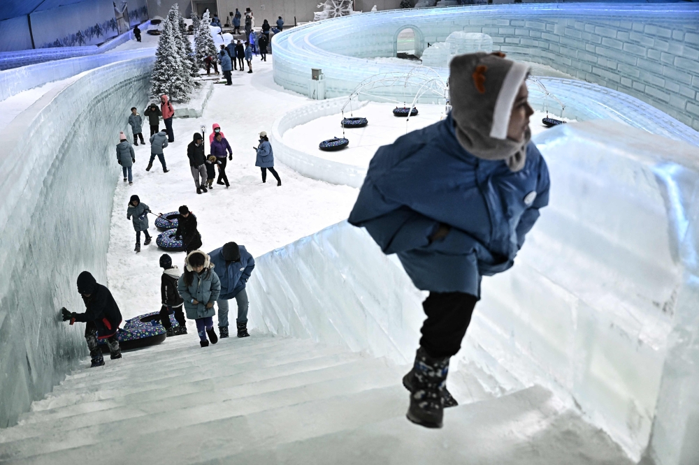 Visitors climb stairs in sub-zero temperatures at the Ice Magic: Fantasy On Ice indoor traveling event by Apollo Media, in Bangkok on April 19, 2023, amidst a heatwave across the region. Photo by Lillian SUWANRUMPHA / AFP