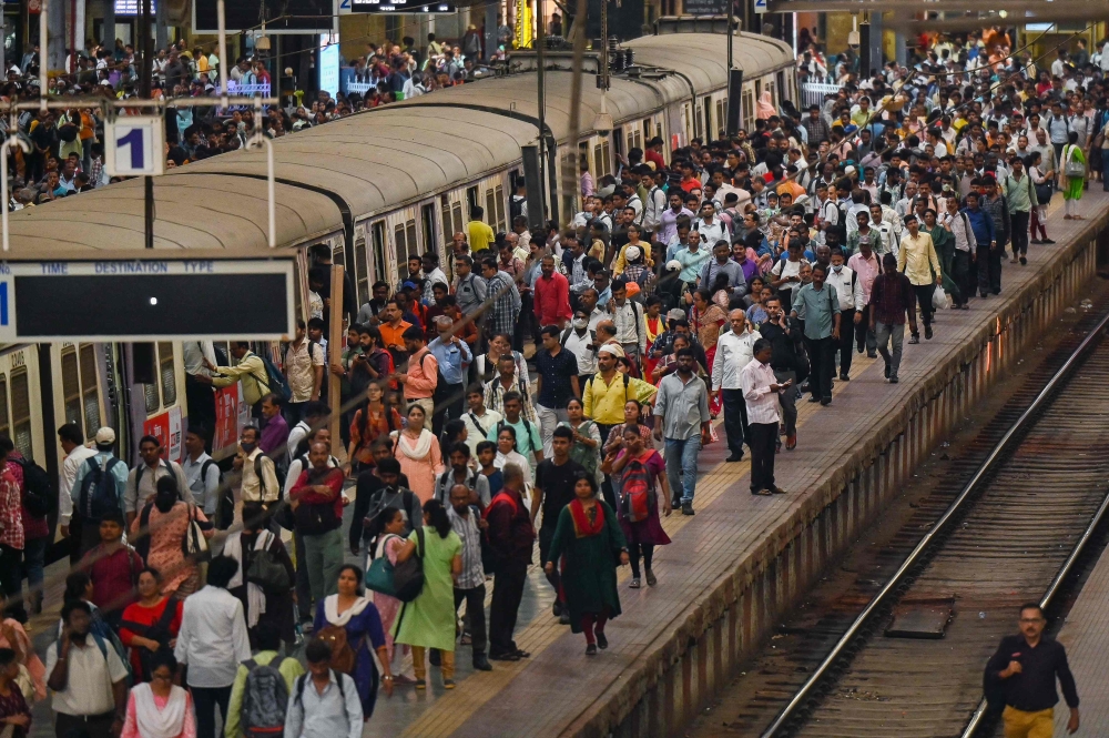 People crowd on platforms as they wait for their train at the Chhatrapati Shivaji Terminus (CST) railway station Mumbai on April 19, 2023. (Photo by Punit Paranjpe / AFP)
