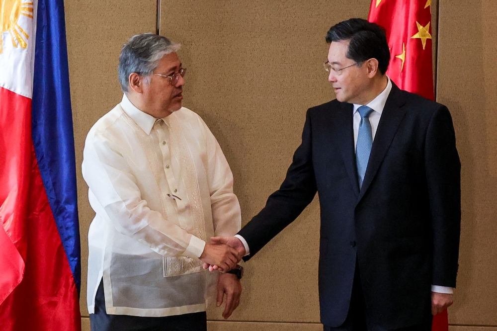 China's Foreign Minister Qin Gang (R) is welcomed by Philippine Foreign Secretary Enrique Manalo ahead of their meeting at the Diamond Hotel in Metro Manila on April 22, 2023. (Photo by Gerard CARREON / POOL / AFP)