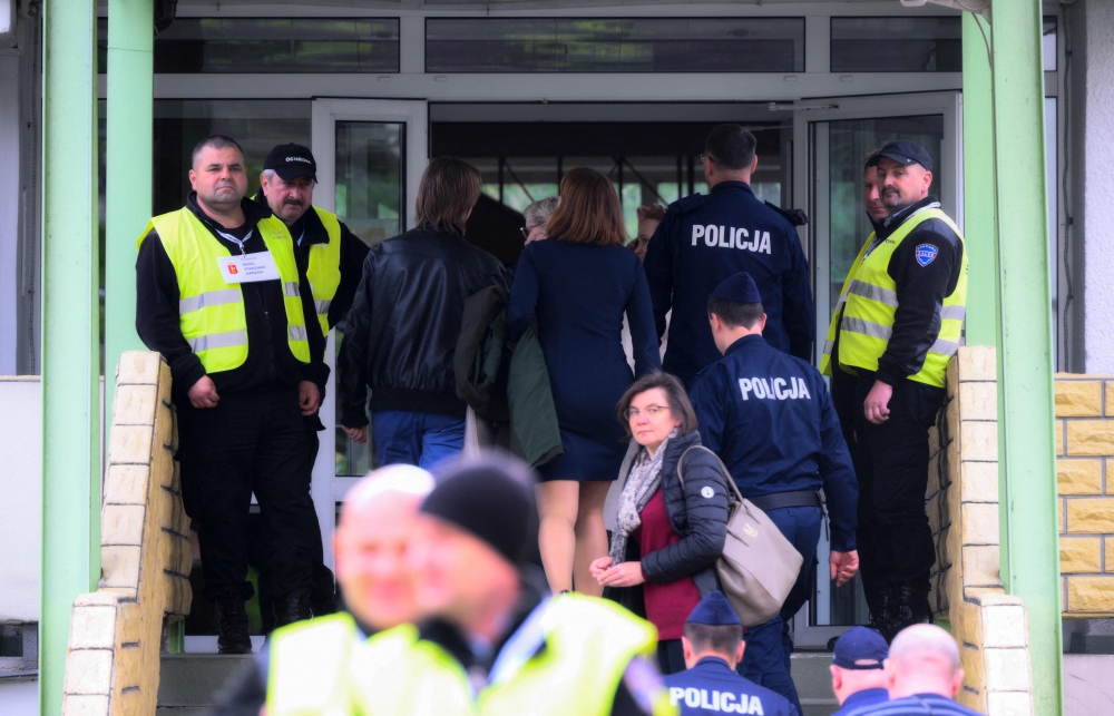 City officials and police are seen entering a a former Russian high school in Warsaw, Poland on April 29, 2023. Photo by Jaap Arriens / AFP
