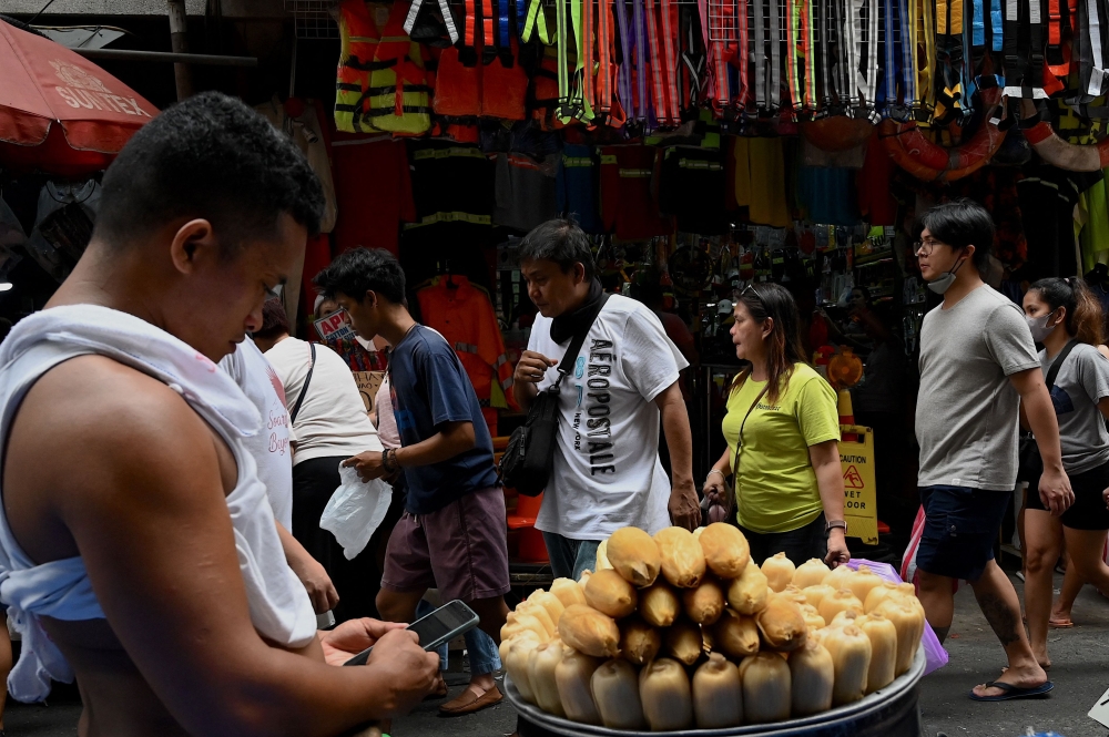A vendor waits for customers along a street in Manila on May 11, 2023. (Photo by Jam Sta Rosa / AFP)
 