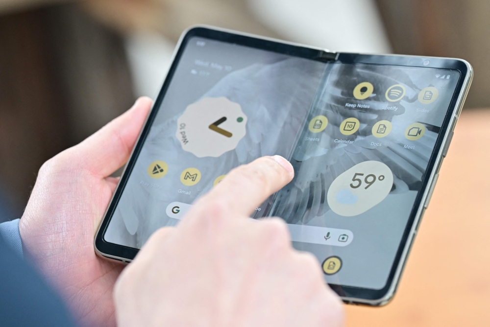 Members of the media view the new Google Pixel Fold phone during the Google I/O annual developers conference at Shoreline Amphitheatre in Mountain View, California on May 10, 2023. (Photo by Josh Edelson / AFP)