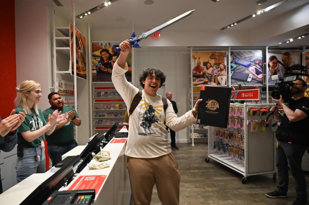 First customer David Castillo wields the Master Sword as he poses for a photo after purchasing 