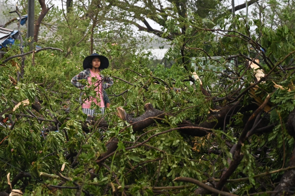 A woman stands amid fallen trees in Kyauktaw in Myanmar's Rakhine state on May 14, 2023 after Cyclone Mocha made landfall.  (Photo by Sai Aung MAIN / AFP)
