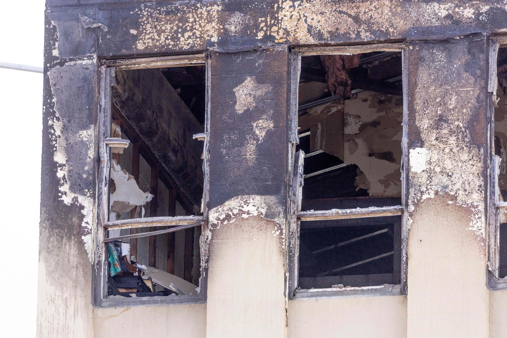 A burnt out window is seen at the Loafers Lodge hostel in the aftermath of a fire in the suburb of Newtown in Wellington on May 17, 2023. Photo by Marty MELVILLE / AFP