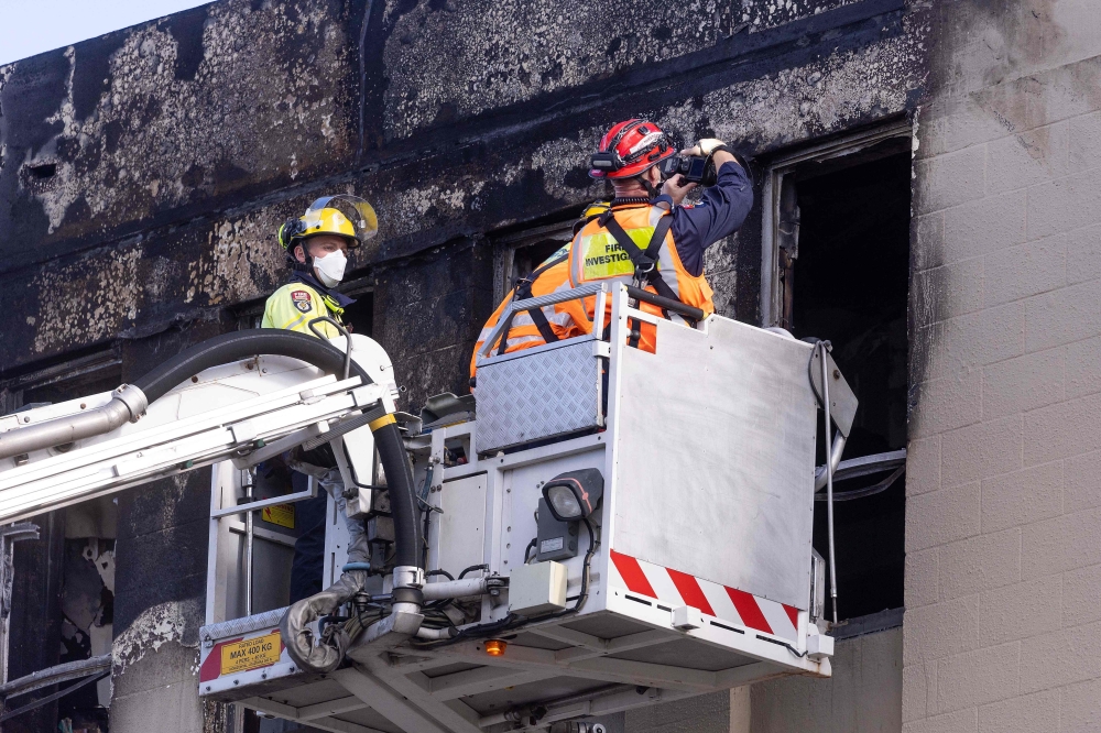 Firefighters inspect the Loafers Lodge hostel where a fire broke out a day earlier in the suburb of Newtown in Wellington on May 17, 2023. Photo by Marty MELVILLE / AFP