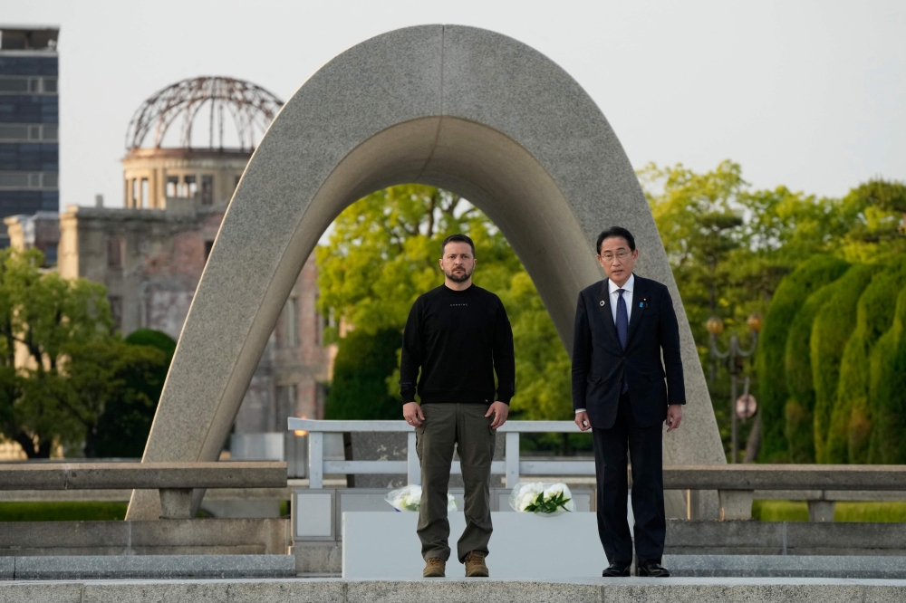 Japan's Prime Minister Fumio Kishida (R) and Ukraine's President Volodymyr Zelensky pose for a photo after laying wreaths in front of the Cenotaph for the Victims of the Atomic Bomb at the Hiroshima Peace Memorial Park in Hiroshima on May 21, 2023. (Photo by Eugene Hoshiko / POOL / AFP)