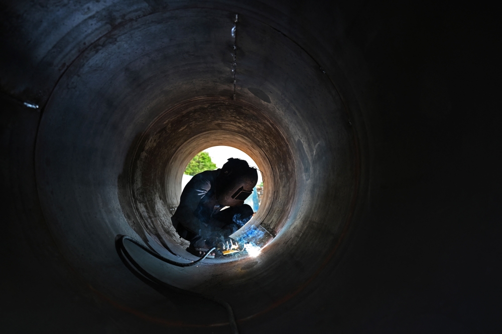 A labourer works at a construction site in Chennai on May 22, 2023. (Photo by R.Satish Babu / AFP)