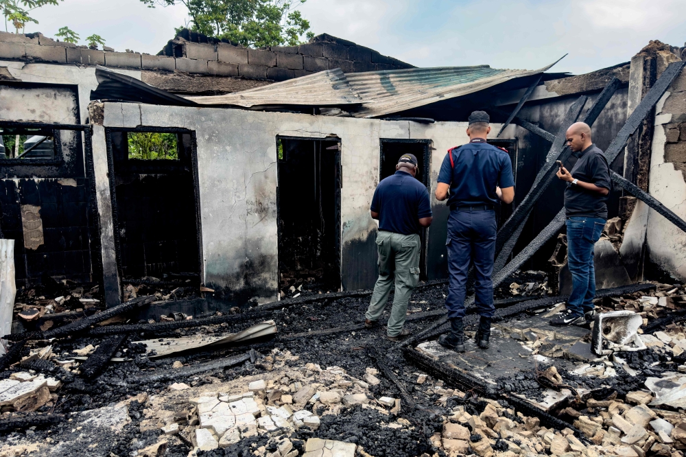 Investigators and government employees inspect the school dormitory where a fire killed at least 19 people in Mahdia, Guyana on May 22, 2023. (Photo by Keno George / AFP)