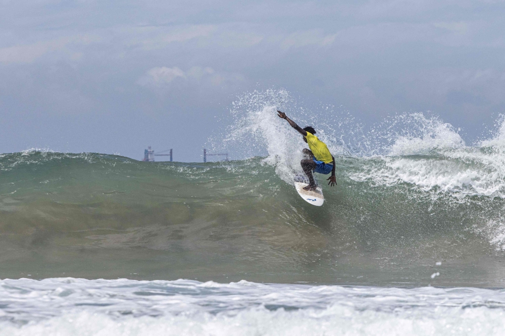 A surfer rides a wave at a surfing competition held at the Tarkwa Bay beach in Lagos Nigeria on 21 May, 2023. (Photo by Benson Ibeabuchi / AFP)
