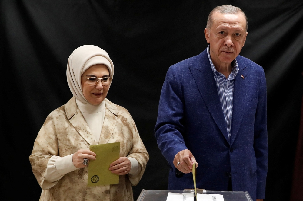 Turkey's President and presidential candidate of AK Party Recep Tayyip Erdogan (R), flanked by his wife Emine Erdogan (L), casts his ballot on the day of the Presidential runoff vote in a school in Istanbul on May 28, 2023. Photo by MURAD SEZER / POOL / AFP