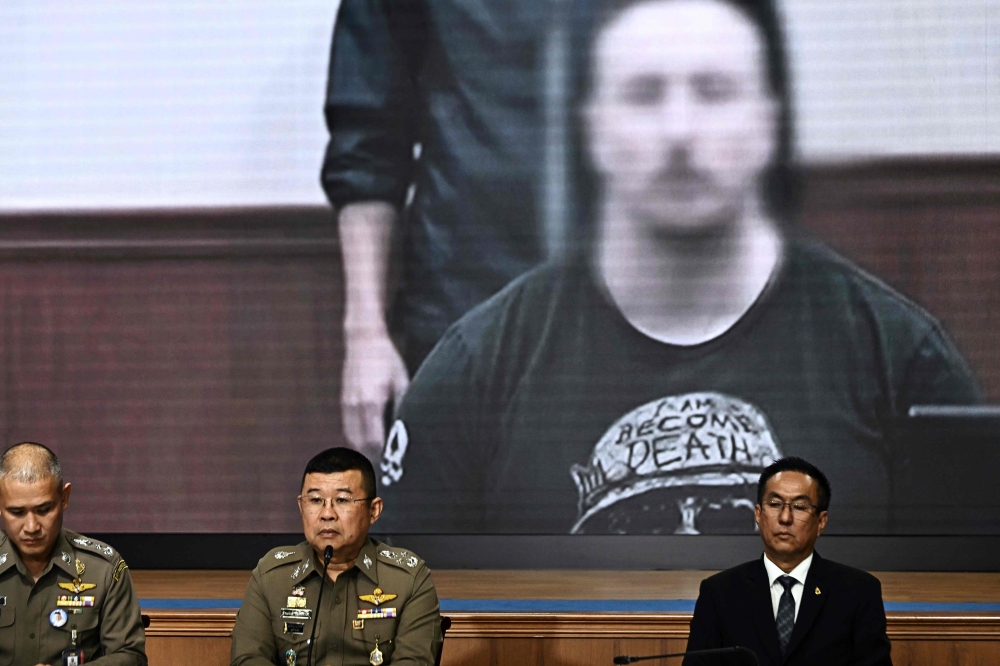 National Police Chief Damrongsak Kittiprapas (C) speaks during a press conference regarding the extradition of Matthew Dupre (on screen), a Canadian man wanted over the suspected murder of Indian gangster Jimi 'Slice' Sandhu in Phuket on February 4, 2022, at the Crime Suppression Division in Bangkok on May 29, 2023. (Photo by Lillian SUWANRUMPHA / AFP)