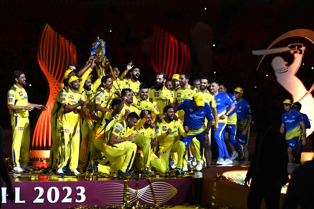 Chennai Super Kings' players celebrate with the trophy after their victory against Gujarat Titans in the Indian Premier League (IPL) Twenty20 final cricket match at the Narendra Modi Stadium in Ahmedabad on May 30, 2023. (Photo by Sajjad Hussain / AFP)