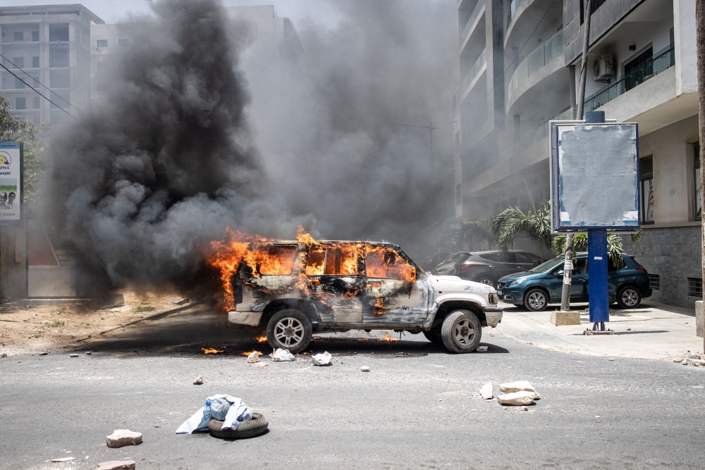 A car set ablaze by demonstrators is pictured in Dakar, on June 1, 2023 during a protest. (Photo by JOHN WESSELS / AFP)