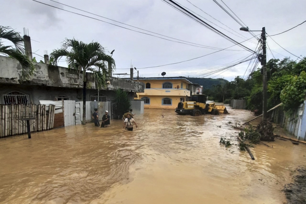 People wade through a flooded street in Esmeraldas, Ecuador, on June 4, 2023. Photo by Luis Cheme / AFP