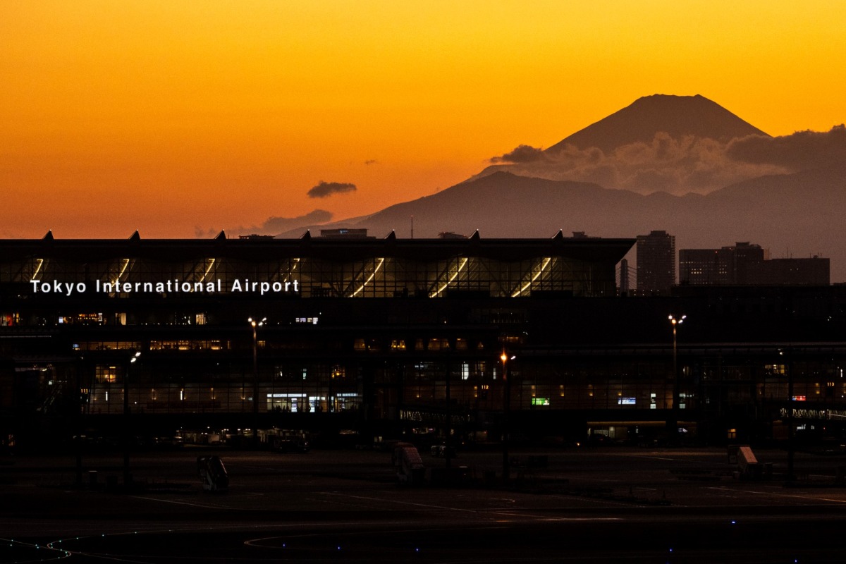 A general view shows the terminal building of Haneda Airport with Mount Fuji (back-R) from the airport's observation deck in Tokyo on February 28, 2023. (Photo by Philip FONG / AFP)