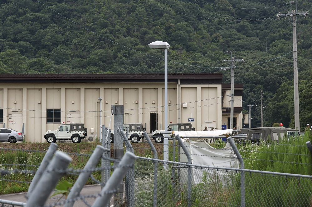 Vehicles and members of Japan's Ground Self-Defense Force (SDF) are pictured outside a building at the Hino basic firing range in the city of Gifu, Gifu prefecture, on June 14, 2023. (Photo by JIJI Press / AFP) 