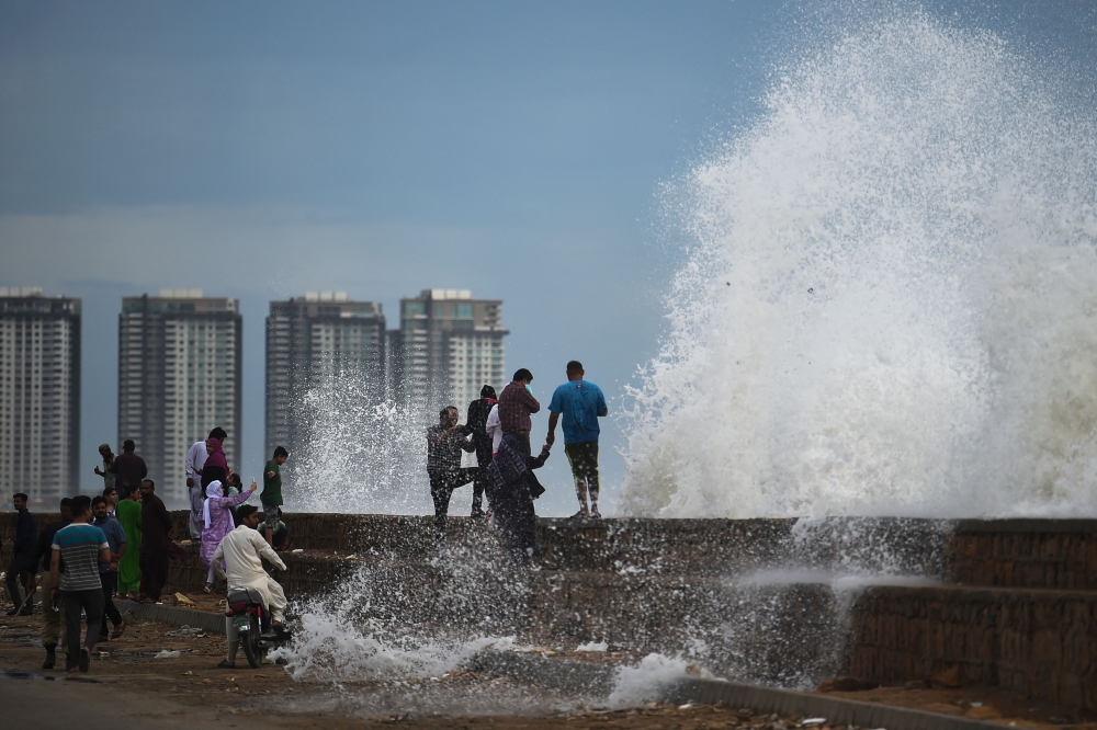 People enjoy high tides splashing on the sea front at a beach before the due onset of cyclone Biparjoy, in Karachi on June 13, 2023. (Photo by Asif Hassan / AFP)