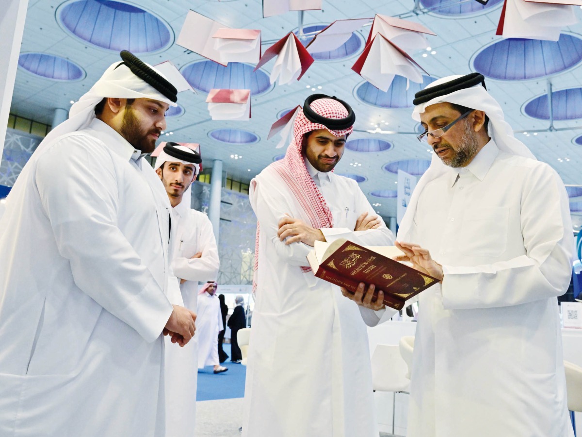 QU President Dr. Hassan Al Derham skims through a book at the QU pavilion.