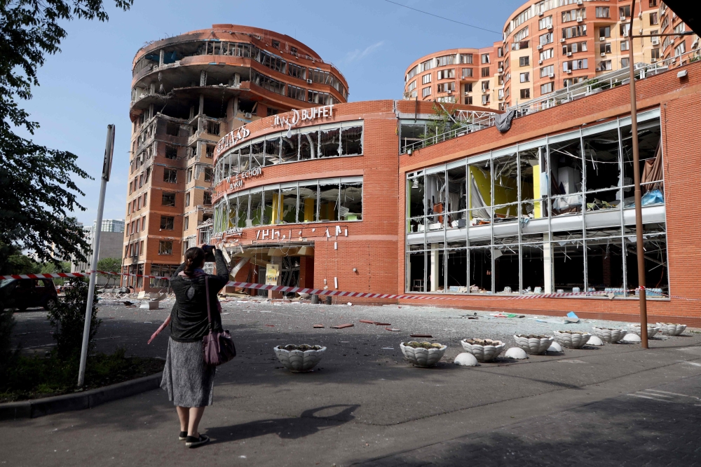 A girl takes a picture of a commercial building, which was damaged after an overnight Russian strike in Odesa on June 14, 2023. Photo by Oleksandr GIMANOV / AFP
