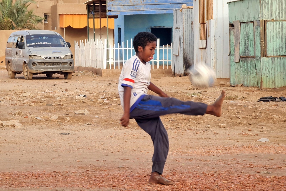 A child plays with a football along a street in Khartoum on June 14, 2023. (Photo by AFP)