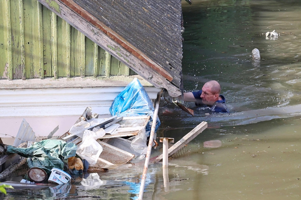 File photo: A local resident swims by a house in a flooded area in Kherson on June 7, 2023, following the destruction of Kakhovka hydroelectric power plant dam. (Photo by Olexander Kornyakov / AFP)


