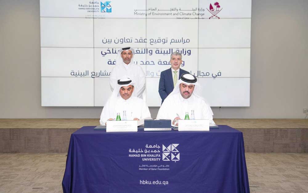 Minister of Environment and Climate Change H E Sheikh Dr. Faleh bin Nasser bin Ahmed bin Ali Al Thani (standing left) and President of Hamad Bin Khalifa University (HBKU) Dr. Ahmad Mujahid Omar Hasnah (standing right) witness the signing ceremony.