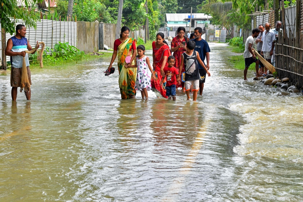 People wade through a flooded road in Ghograpar village of Nalbari district, in India's Assam state. (Photo by Biju BORO / AFP)