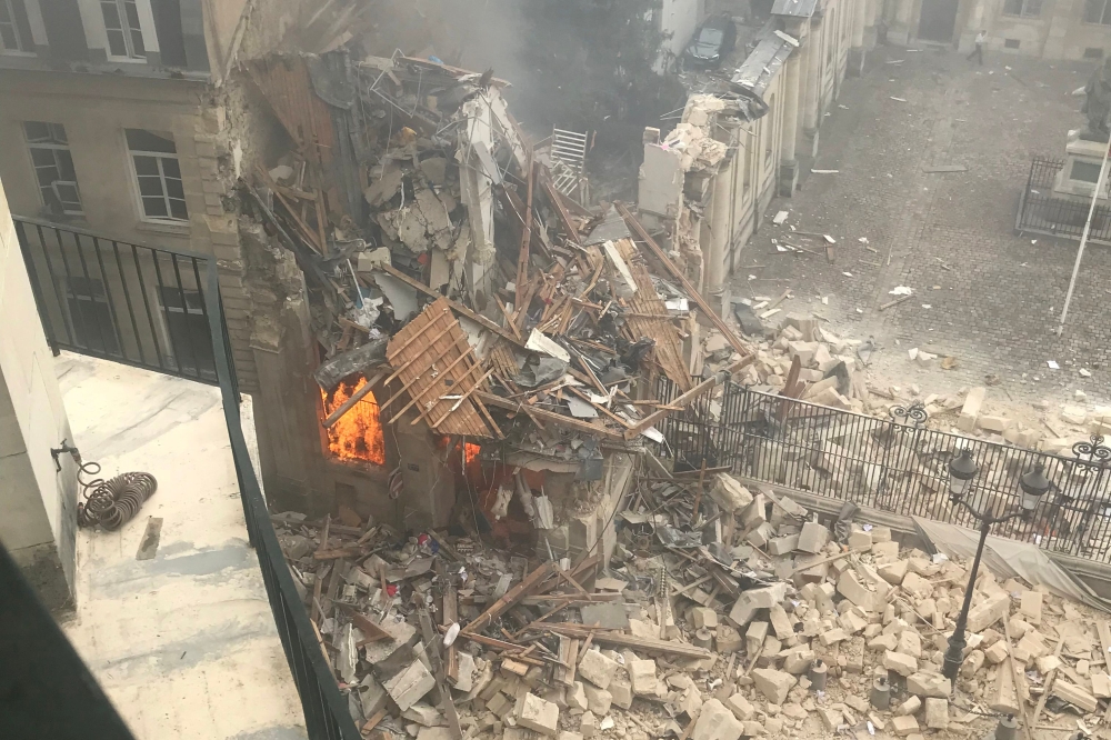This photograph taken on June 21, 2023, shows the flames emerging from the destruction and rubble in the immediate aftermath of an explosion in a building on Rue Saint-Jacques near Place Alphonse-Laveran in the 5th arrondissement of Paris. Photo by Gregory Custo / AFP

