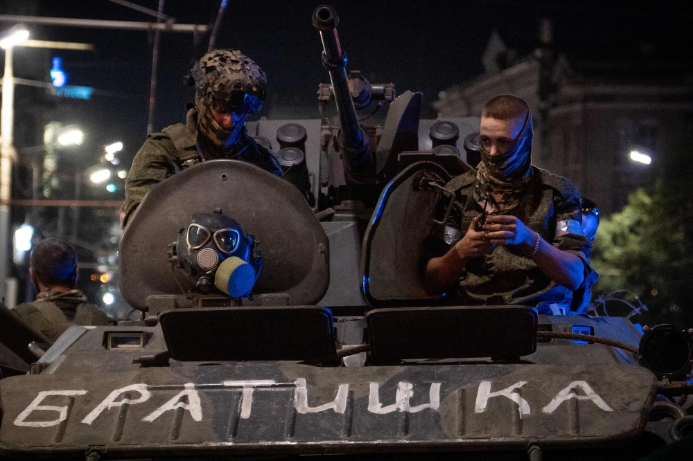 Members of Wagner group looks from a military vehicle with the sign read as 