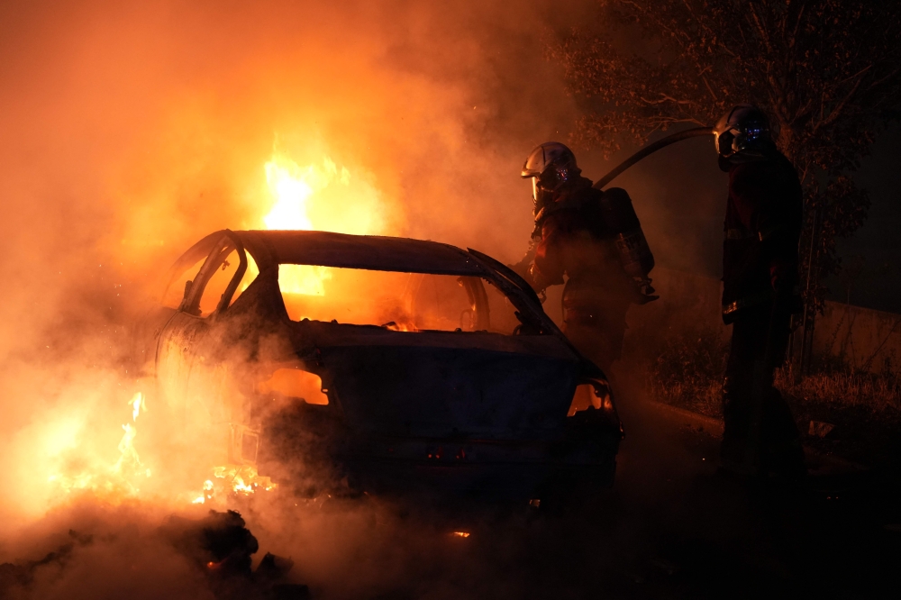 French firefighters extinguish burning vehicles following protests in Nanterre, west of Paris, on June 28, 2023, a day after a 17-year-old boy was shot in the chest by police at point-blank range in this western suburb of Paris. (Photo by Zakaria ABDELKAFI / AFP)
