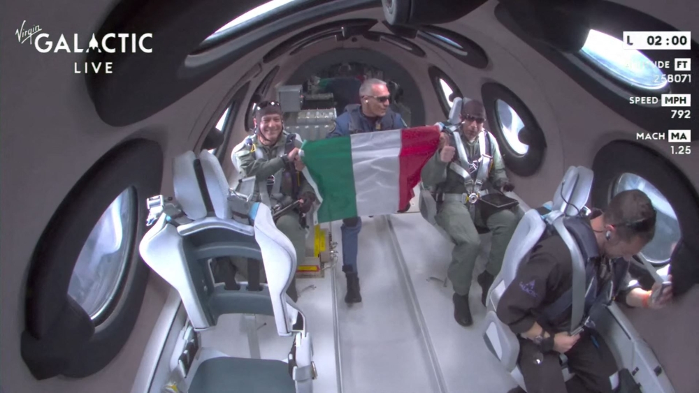 This still image from a Virgin Galactic video shows Galactic 01 mission crew members from the Italian Air Force display the Italian flag as they reach space during the first commercial flight from Spaceport City in New Mexico on June 29, 2023. (Photo by Jose Romero / Virgin Galactic / AFP)