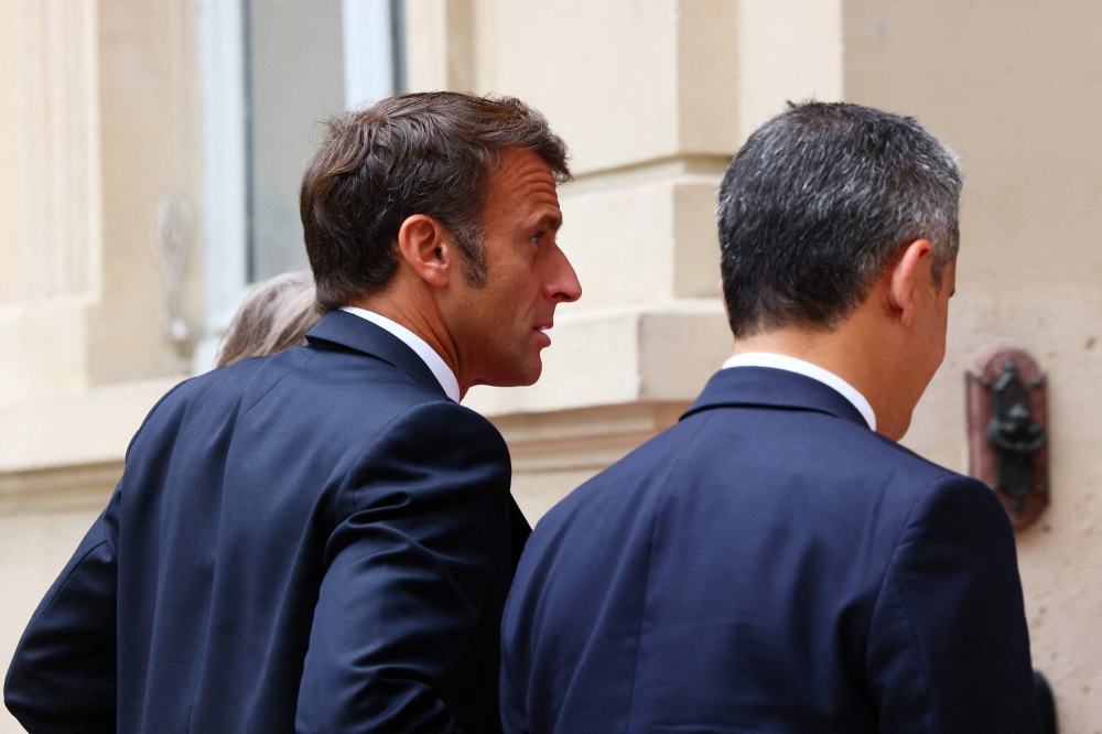 French President Emmanuel Macron (L) and French Interior and Overseas Minister Gerald Darmanin arrive to attend a intermninisterial crisis unit (Cellule interministerielle de crise - CIC) meeting after riots erupted for the third night in a row across the country following the death of Nahel, a 17-year-old teenager killed during a traffic stop in Nanterre by a French police officer, at the emergency crisis center of the Interior Ministry in Paris, France, June 30, 2023. (Photo by YVES HERMAN / POOL / AFP)
