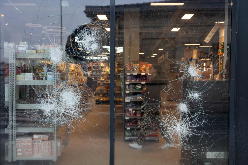An employee is seen behind the broken windows of a supermarket following a fourth consecutive night of rioting in France sparked by the death of teenage driver Nahel by a police bullet, in Talence, south-western France on July 1, 2023. (Photo by ROMAIN PERROCHEAU / AFP)
