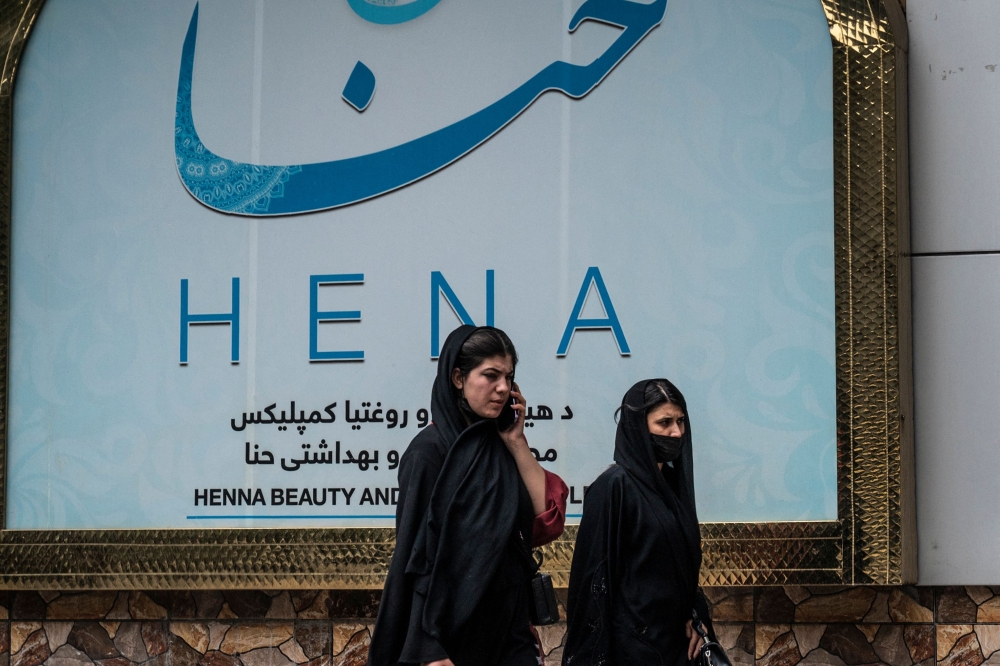 Women walk past a beauty salon at the Shahr-e Naw area in Kabul on July 4, 2023. (Photo by Wakil Kohsar / AFP)

