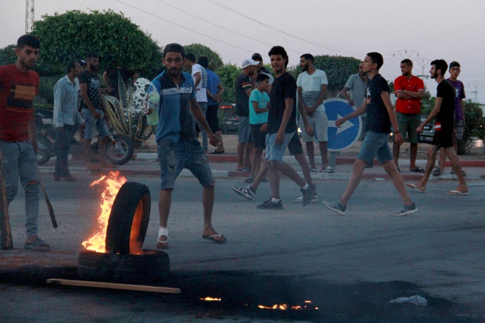 Tunisian youths block the road to migrants by setting tyres on fire as tensions rose in Sfax after the burial of a young Tunisian stabbed to death during a scuffle between residents and migrants from sub-Saharan Africa, on July 4, 2023. (Photo by HOUSSEM ZOUARI / AFP)
